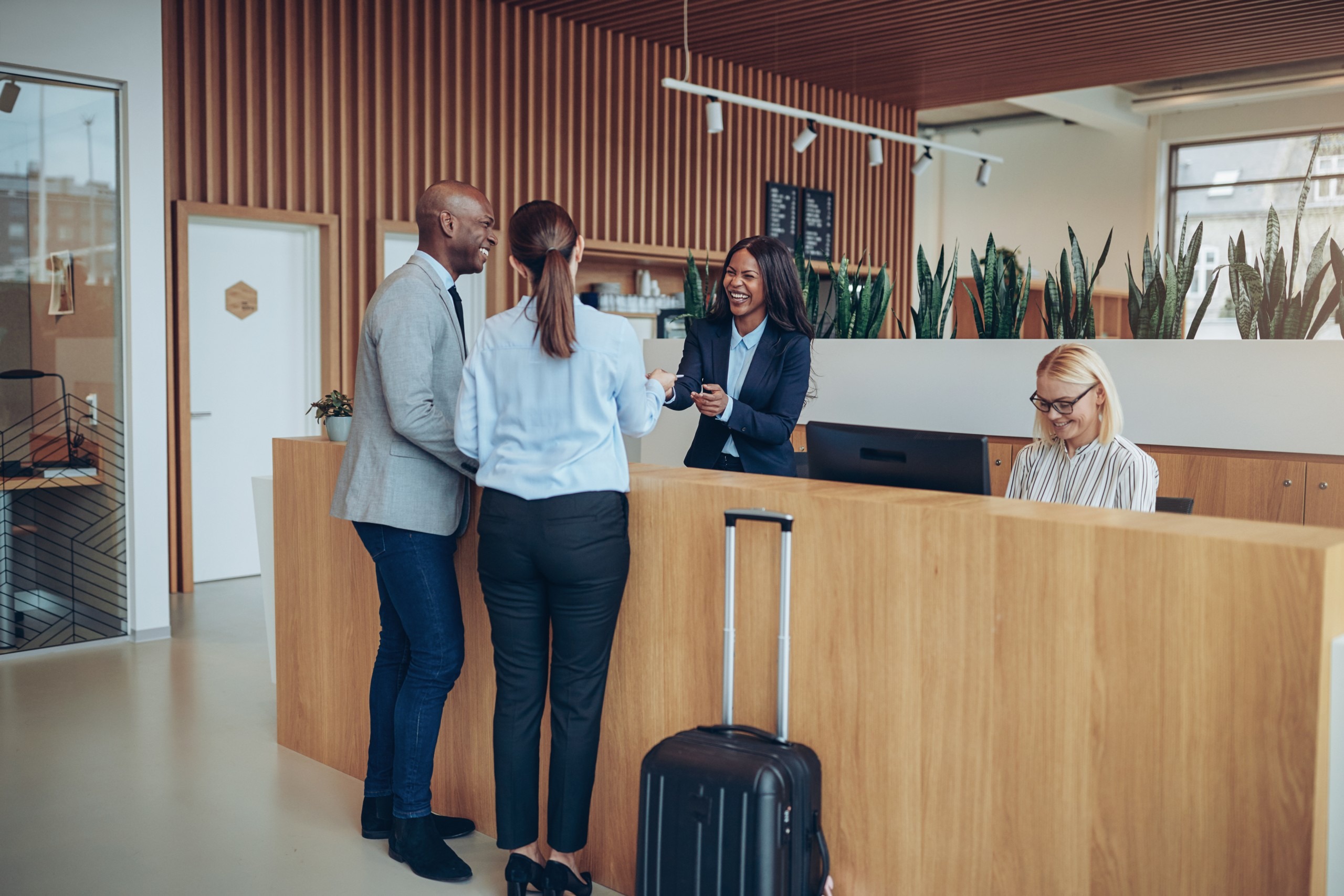 Two smiling guests giving their reservation information to hotel