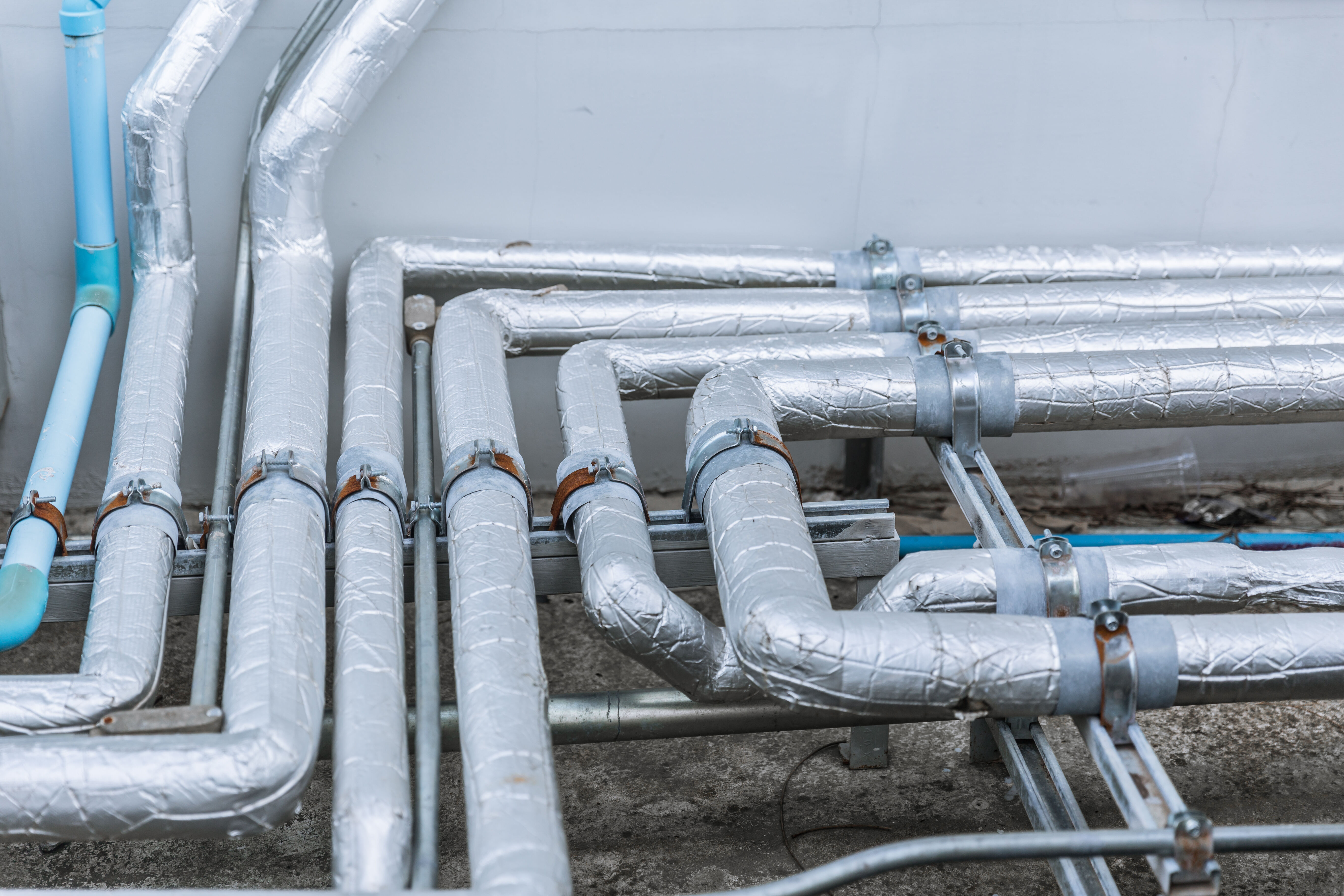 Image of numerous commercial building pipes wrapped in silver insulation